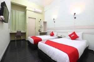 two beds in a hotel room with red pillows at Hotel O Green Mango @ Sri Cemerlang in Kota Bharu