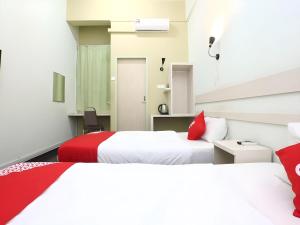 two beds with red pillows in a room at Hotel O Green Mango @ Sri Cemerlang in Kota Bharu