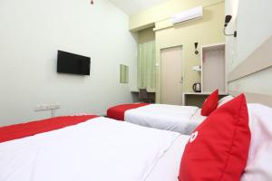 two beds with red pillows in a room at Hotel O Green Mango @ Sri Cemerlang in Kota Bharu
