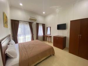 a bedroom with a bed and a flat screen tv at Capital O 91094 Hotel & Chalet Sportfishing in Batu Ferringhi +33 photos