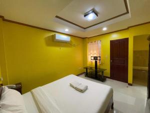 a bedroom with yellow walls and a bed with towels on it at Casa Venicia Caticlan in Boracay +16 photos