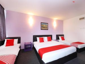 a room with two beds with red and white pillows at Hotel O Marvelton Hotel in Butterworth