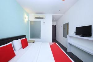 a bedroom with a bed with red pillows and a tv at Hotel O Marvelton Hotel in Butterworth +47 photos