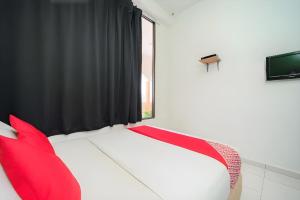 a bedroom with a bed with red pillows and a window at Hotel O My Budget Home in Batu Ferringhi