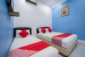 two beds sitting next to each other in a bedroom at Hotel O My Budget Home in Batu Ferringhi