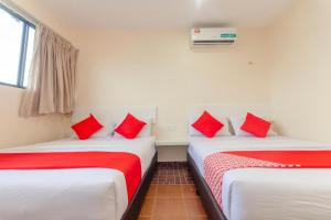two beds in a room with red pillows on them at Skudai Hotel in Skudai