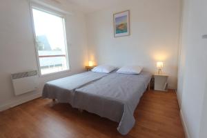 a bedroom with a bed with two pillows and a window at Fouesnant Beg Meil, duplex au coeur du village, à 450 m de la plage in Beg-Meil