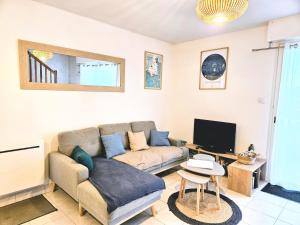 a living room with a couch and a tv at Fouesnant Beg Meil, duplex au coeur du village, à 450 m de la plage in Beg-Meil