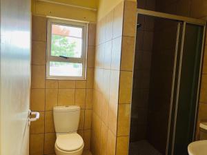 a bathroom with a toilet and a window at Koshoka Suites in Ongwediva