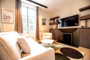 a living room with a white couch and a flat screen tv at Sentez vous comme chez vous au coeur du Marais in Paris