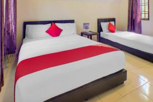 a bedroom with two beds with red pillows at Hotel O Sedili Inn Resort in Kota Tinggi