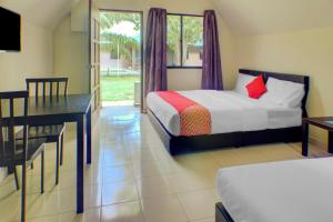a bedroom with two beds and a table and a desk at Hotel O Sedili Inn Resort in Kota Tinggi