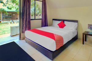 a bedroom with a bed with a red pillow at Hotel O Sedili Inn Resort in Kota Tinggi