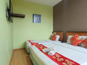 a bedroom with two beds with red and white pillows at Hotel O Melody 88 Inn in Miri