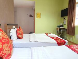a hotel room with two beds with red and white pillows at Hotel O Melody 88 Inn in Miri