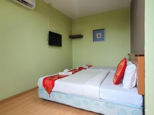 a bedroom with a bed with white sheets and red pillows at Hotel O Melody 88 Inn in Miri +27 photos