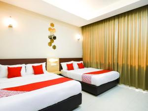 two beds in a hotel room with red pillows at Hotel O La Mirina Boutique Inn in Miri