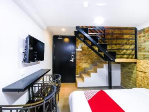 a room with a bed and a staircase and a tv at Hotel O La Mirina Boutique Inn in Miri