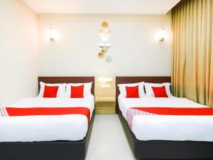 two beds in a hotel room with red pillows at Hotel O La Mirina Boutique Inn in Miri
