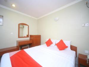 a bedroom with a bed with red pillows and a mirror at Hotel O London in Sandakan +19 photos
