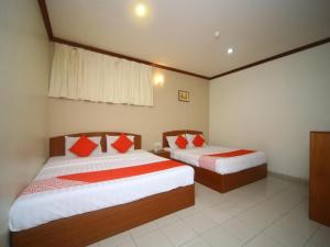 a bedroom with two beds with red and white pillows at Hotel O London in Sandakan