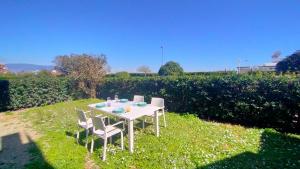 a white table and chairs sitting in the grass at Appartamento trilocale FRONTE MARE con SPIAGGIA INCLUSA Taunus vacanze cod 494 in Marcelli +3 photos