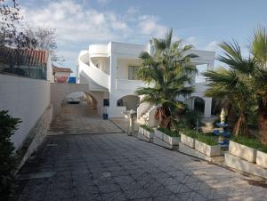 Un edificio blanco con una pasarela y palmeras. en Raucci House, en Torre Squillace
