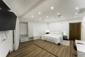 a white bedroom with a bed and a tv at Hotel Rural Alecook in Valcabado +36 photos