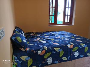 un letto con un piumone blu e una finestra di The Kodai Fantasy a Kodaikānāl