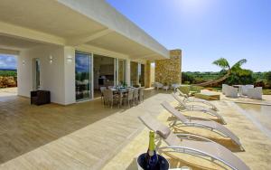 a patio with chairs and a table and a dining room at Villa Infinito by PosarelliVillas in Castelvetrano Selinunte