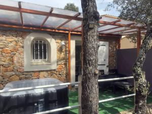 ein Steinhaus mit einem Whirlpool und einem Baum in der Unterkunft votre Cocon en pierre et son spa en option gîte le repos des chênes in Régusse
