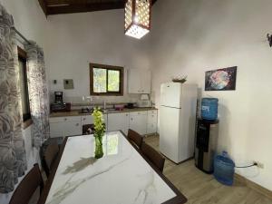 a kitchen with a table and a white refrigerator at Villa Jarabacoa Monte Bonito in Jarabacoa