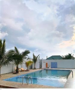 a swimming pool with palm trees and a building at First HR Hotel in Prampram