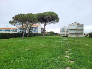 un champ herbeux avec deux arbres et un bâtiment dans l'établissement Appartement avec piscine et accès direct à la mer, à Châtelaillon-Plage