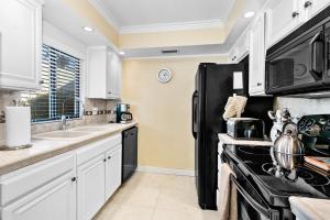 a kitchen with white cabinets and a black refrigerator at Ranch Club Serenity in Palm Springs +10 photos