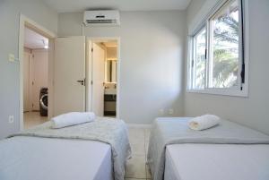 zwei Betten in einem weißen Zimmer mit Fenster in der Unterkunft Elegante Casa com Piscina - João Paulo - CEN006 in Florianópolis + 56 Fotos