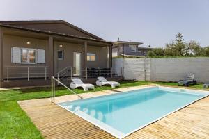 ein Schwimmbecken mit zwei Stühlen und ein Haus in der Unterkunft NeSo - Villa Fyllo with Pool steps from the Beach in Tavronítis