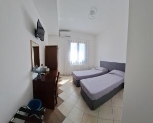 a bedroom with two beds and a desk and a television at Mariposa B&B in San Vito lo Capo