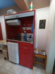 a red kitchen with a sink and a stove at Blue Dolphins 2 bedroomed house with court yard in Skiathos Town