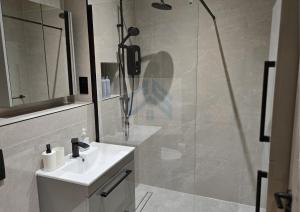 ein Badezimmer mit einem weißen Waschbecken und einer Dusche in der Unterkunft Bright Finchley Apartments - Perfect for Business & Leisure in Finchley + 16 Fotos