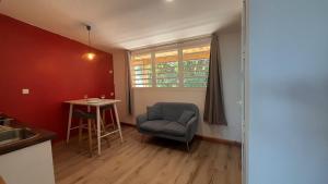 a room with a chair and a table and a window at Cannelle, T2 Cosy Vue Mer à Mont Vert Les Bas in Saint-Pierre