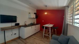 a kitchen with a red wall and a table and a counter at Cannelle, T2 Cosy Vue Mer à Mont Vert Les Bas in Saint-Pierre +2 photos