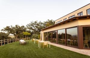 a patio with tables and chairs on the grass at Il Poggio di Teo in Manciano