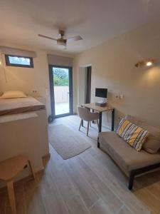 a living room with a couch and a desk with a computer at Pool apartment 5 minutes walk from beach in Porto Rafti