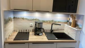 a kitchen counter with a coffee maker and a sink at Appartement mit Balkon und Meerblick in Fehmarn