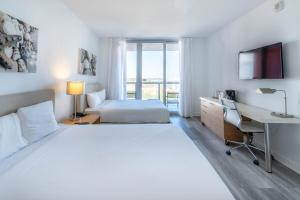 ハランデール・ビーチにある2B 2B Beachfront Pool Gym, and Restaurantのベッドと机とパソコンが備わったホテルの部屋 +18枚の写真