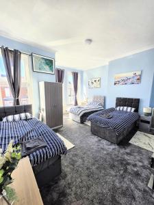 two beds in a room with blue walls at Kings Road Modern Home in Middlesbrough