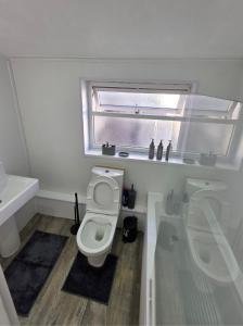 a white bathroom with a toilet and a window at Kings Road Modern Home in Middlesbrough