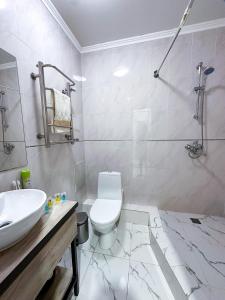 a bathroom with a white toilet and a sink at Уютная квартира в центре событий in Almaty