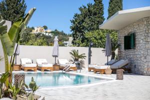a swimming pool with lounge chairs and umbrellas at Lythari Summer Villa in Afantou